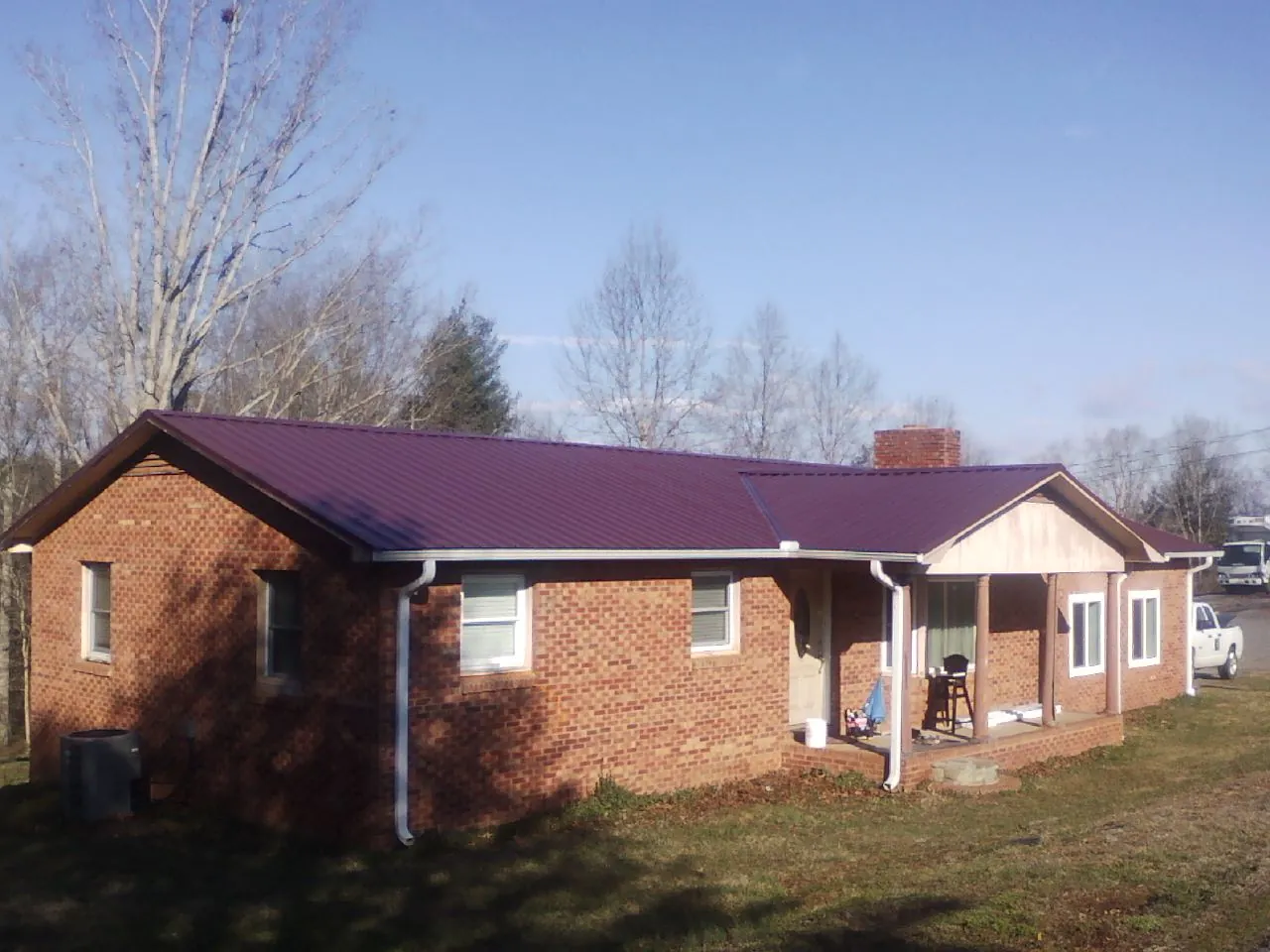 Burgundy metal roof on a brick ranch home with a new addition in Wareham