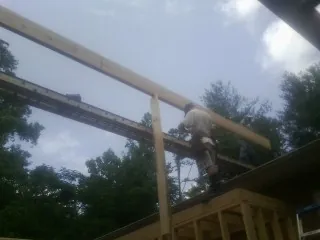 Carpenter setting a ridge beam over a new addition frame — Ice Dam Removal by Roofing Brothers in Wareham