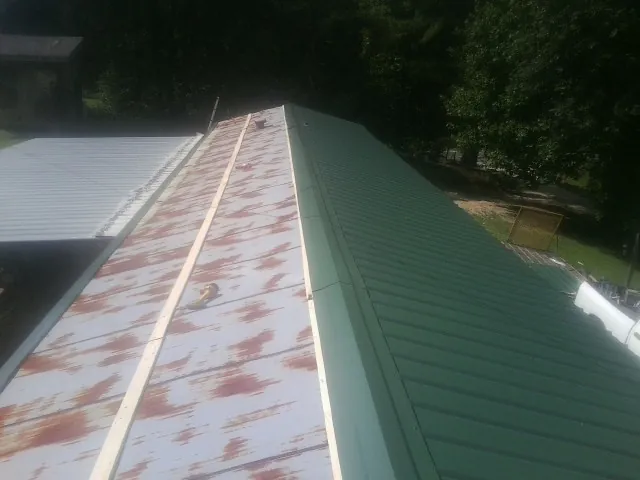 Old rusted panels beside newly installed green metal roofing — Wind Damage Roof Repair by Roofing Brothers in Wareham
