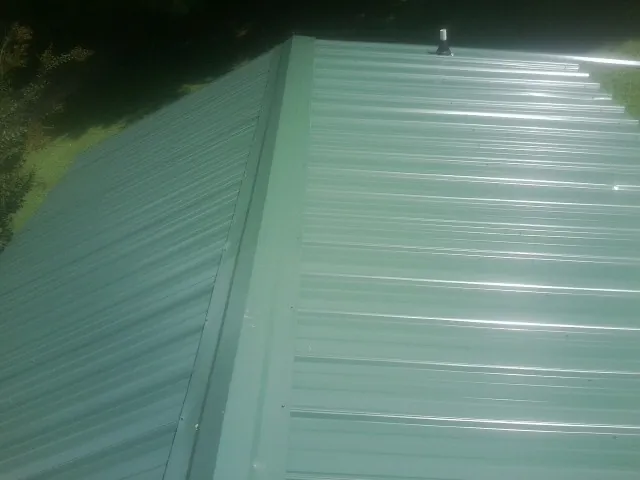 New green metal panels meeting at the ridge of a roof — Flat Roof Repair work by our crew in Wareham