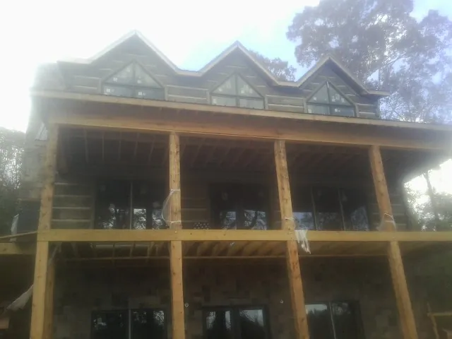 Dormers and porch framing on a large log home under construction — Roof Coating work by our crew in Wareham