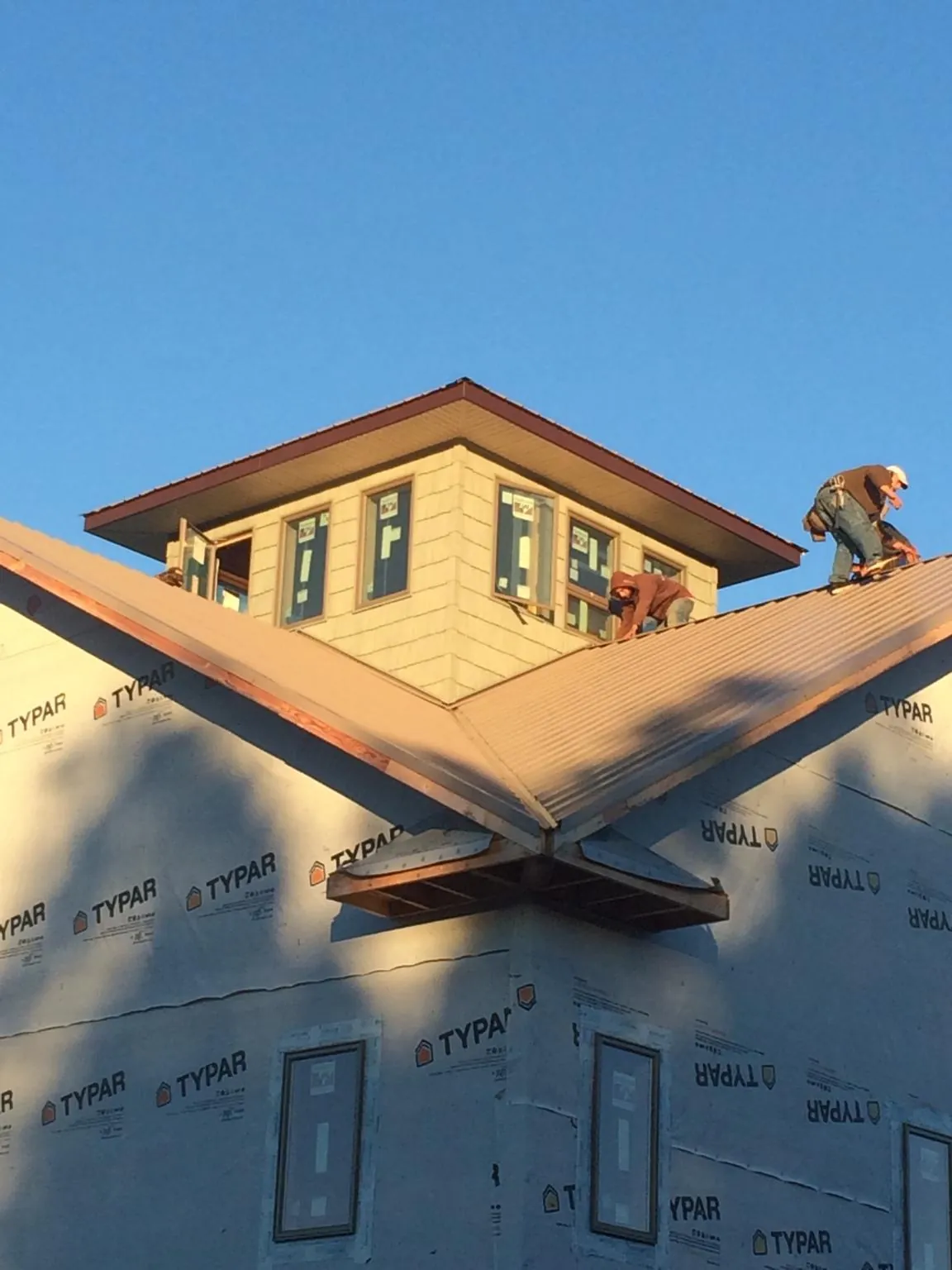 Roofers working around a rooftop cupola on a new metal roof at sunset — Roof Waterproofing in Wareham by Roofing Brothers